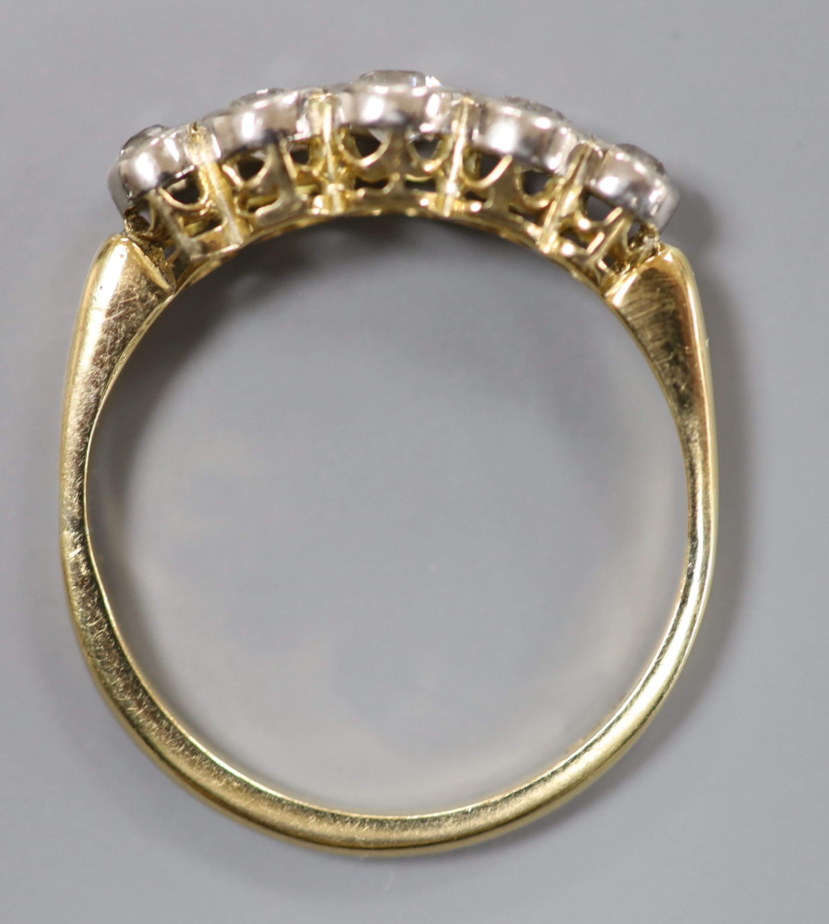 A yellow metal and graduated five stone diamond set half hoop ring, size P/Q, gross 2.6 grams.